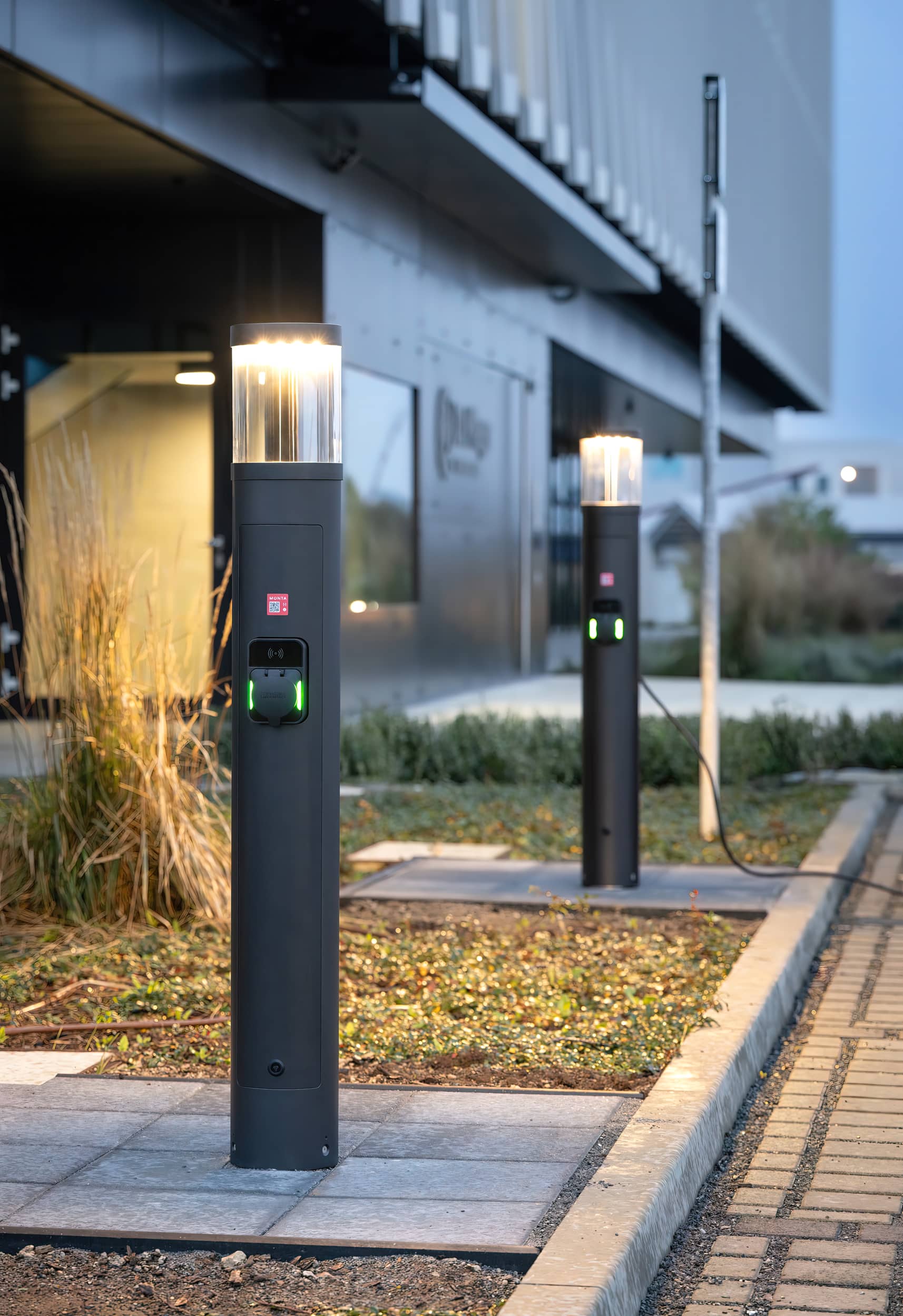 Eichrechtskonforme Licht-/Ladesäulen von RZB Energy auf einem Firmenparkplatz.
