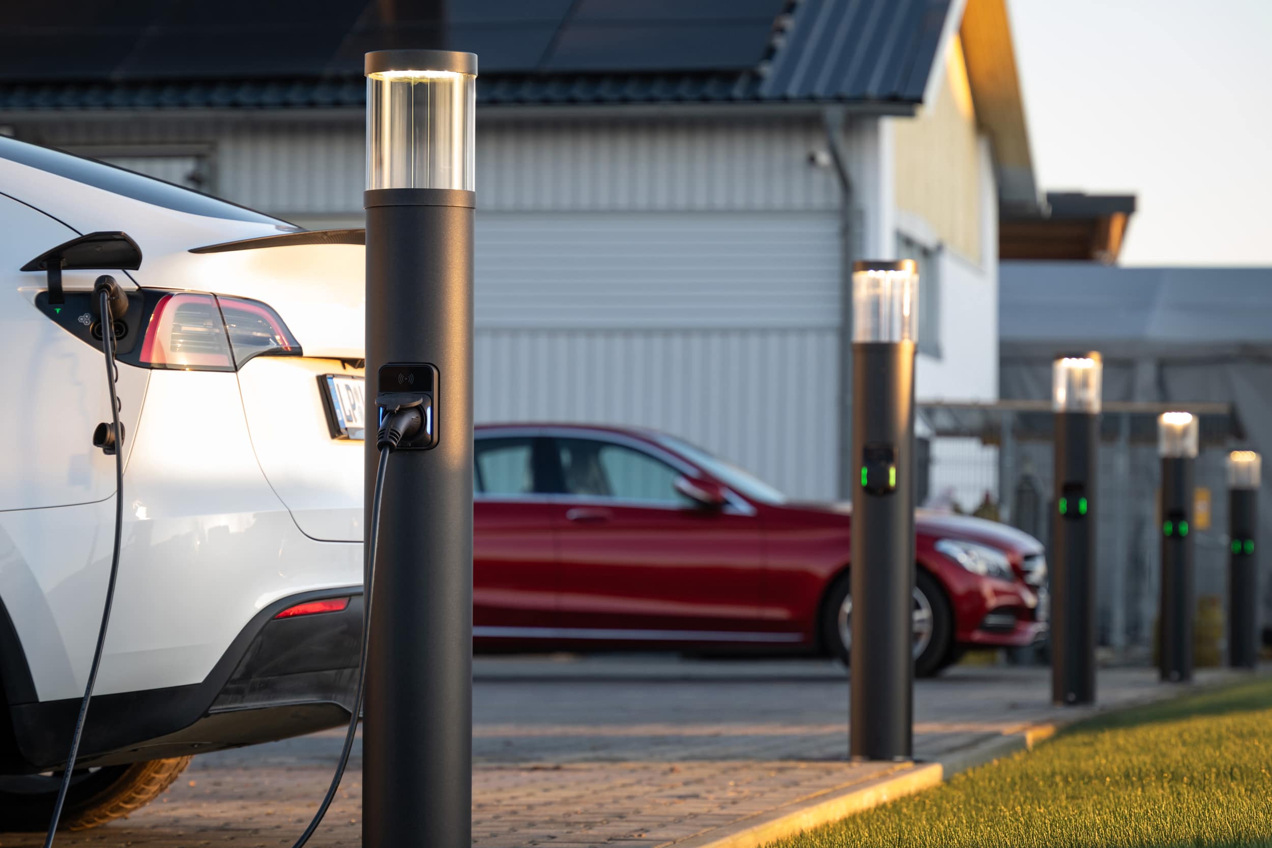 Parkplatz mit 2 E-Autos, die an Lade-/Lichtsäulen von RZB Energy geladen werden.