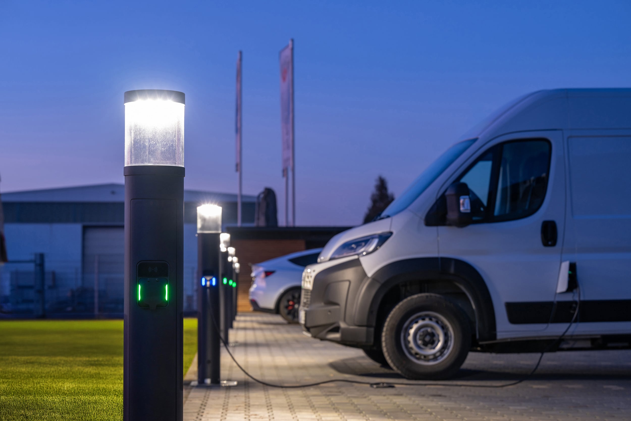 Parkplatz mit Firmenbus, der an einer Lade-/Lichtsäule von RZB Energy geladen wird.
