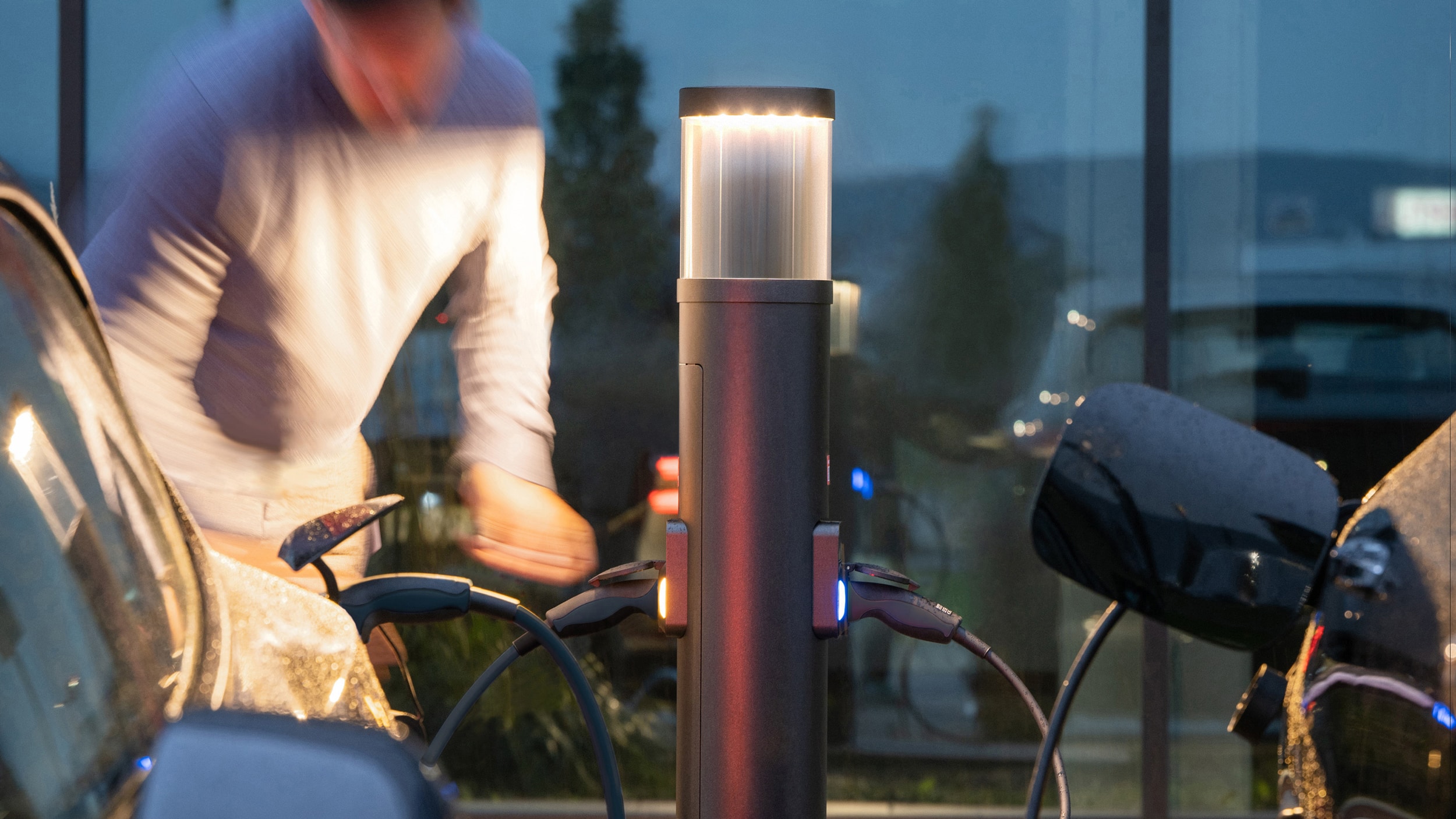 Mann beim Laden seines E-Autos an einer Licht-/Ladesäule von RZB Energy.