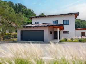Einfamilienhaus und Garagenanbau mit Zeltdach und Gesims über dem Hauseingang von SCE Reisinger Bau.
