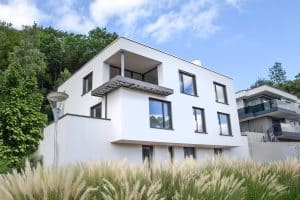 Kubisches, zweistöckiges Einfamilienhaus mit Flachdach und Balkon in Hanglage von SCE Reisinger Bau.