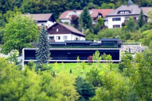Moderne kubische Villa mit Steinfassade und einer überdachten Terrassenfläche mit Glasgeländer von SCE Reisinger Bau.