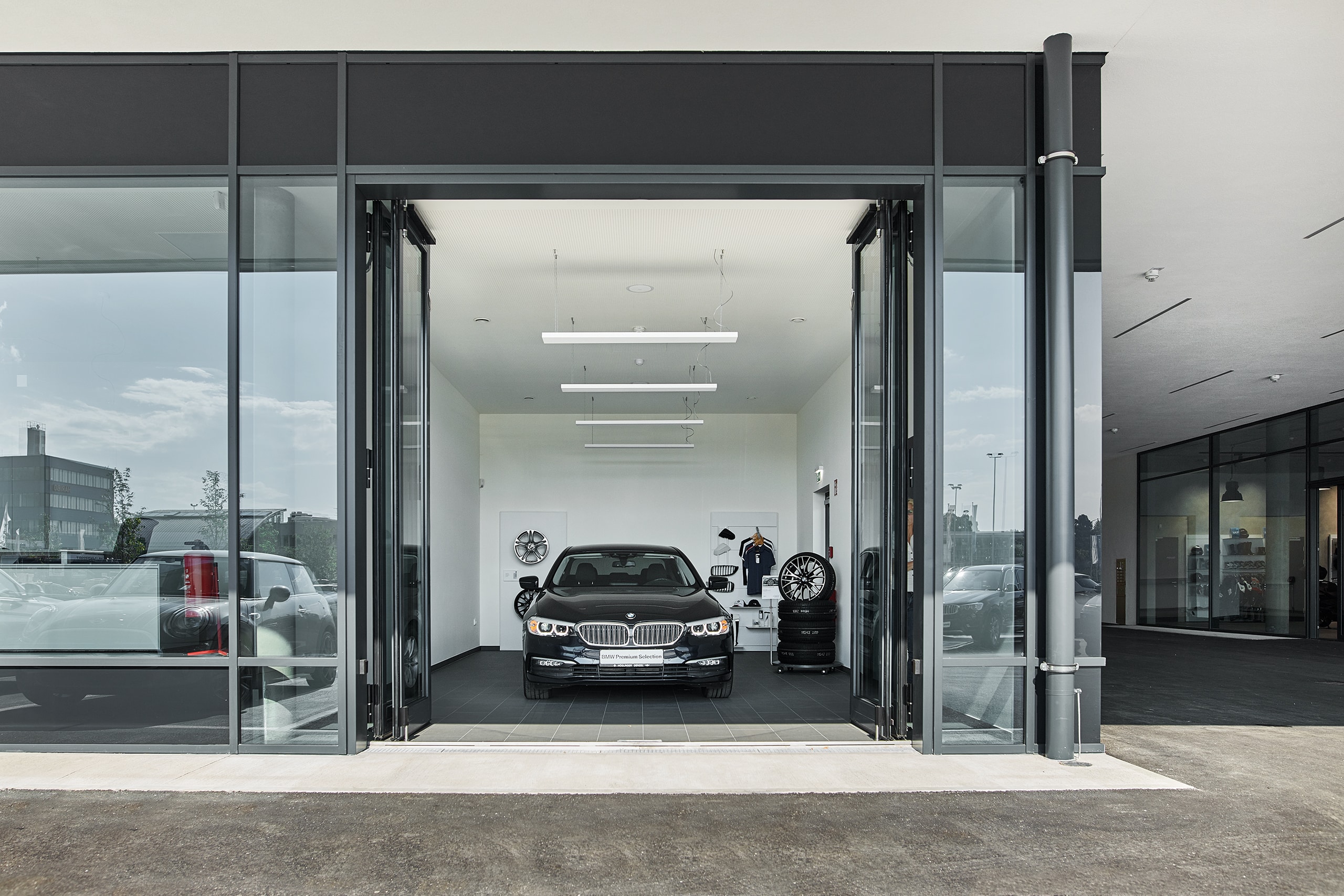SCHNEIDER Torsysteme zeigt ein Autohaus mit einem gewerblichen voll-verglasten Falttore in anthrazit von außen, das geöffnet ist.