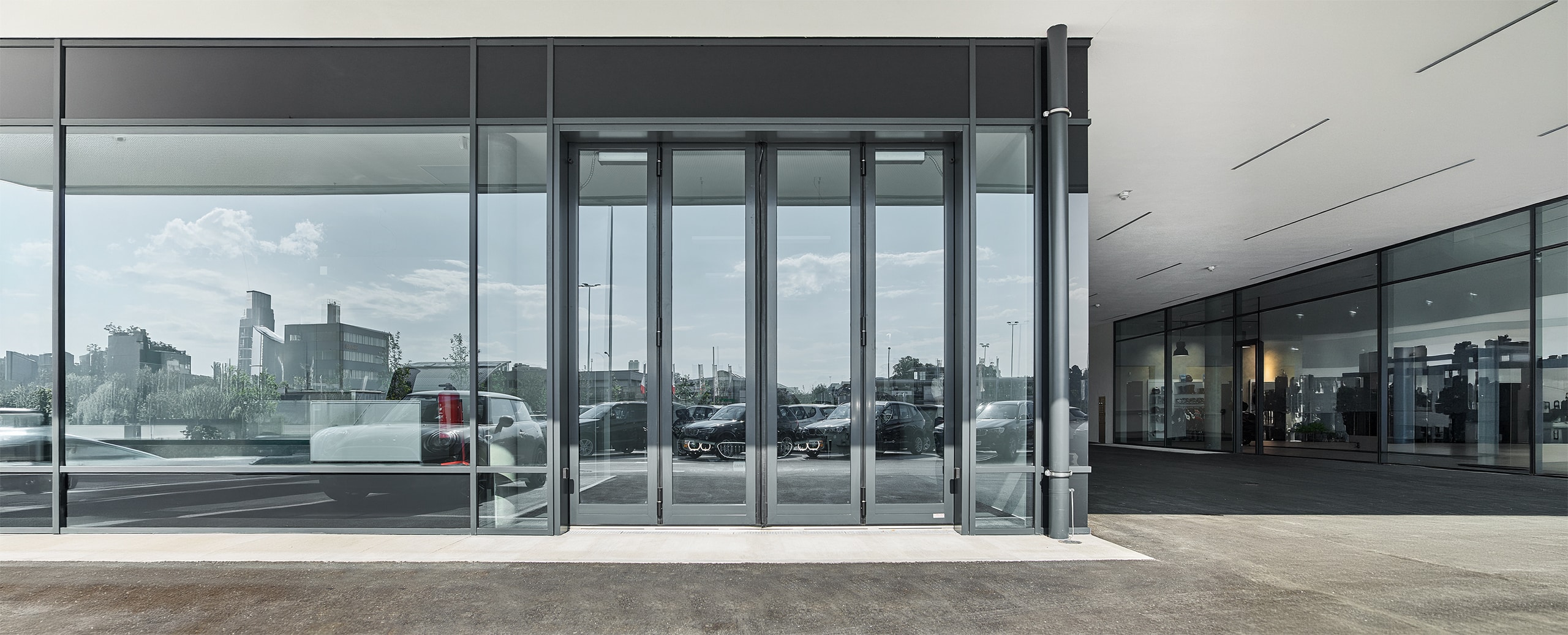 SCHNEIDER Torsysteme zeigt ein Autohaus mit einem gewerblichen voll-verglasten Falttore in anthrazit von außen.