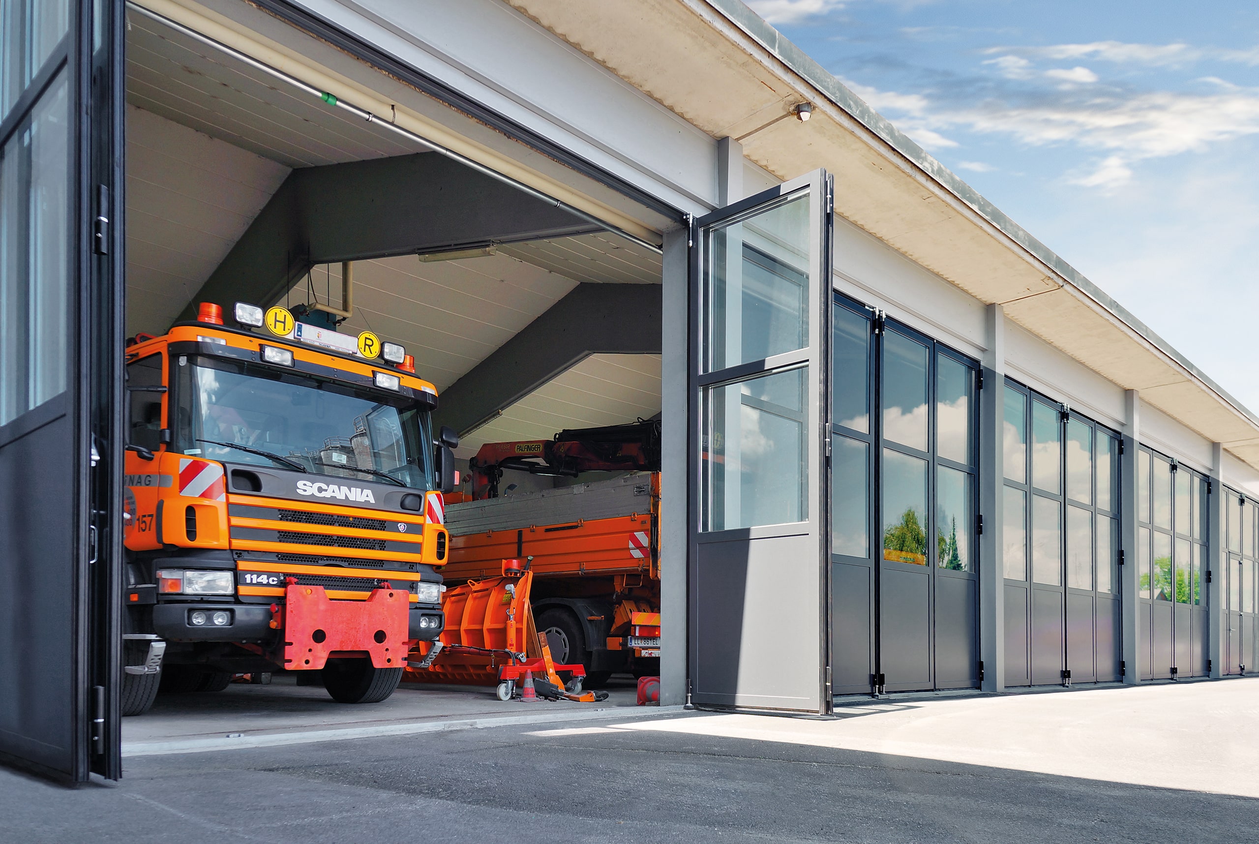 SCHNEIDER Torsysteme zeigt mehrere gewerbliche verglaste Falttore in einem Feuerwehr Einsatzgebäude nebeneinander.