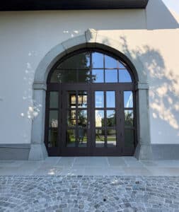 Altbau mit zweiflügeligem geschlossenen Eingangstor mit Holzsprossen, Oberlicht mit Sprossen und Rundbogen, sowie Seitenlichtern, dunkel lackiert von SILBER Fensterbau.