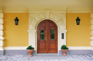 Denkmalgeschütztes Anwesen mit einer zweiflügeligen Hauseingangstüre bzw. Eingangstor in rötlichem Vollholz mit Torbogen und Glaselementen von SILBER Fensterbau.