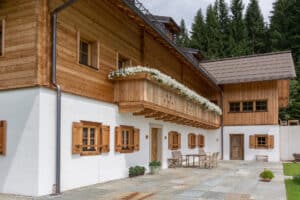 Rustikales Holzhaus mit klassischen Holzsprossenfenstern mit Fensterläden und einem Holzbalkon von SILBER Fensterbau.