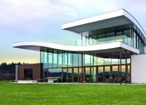 Moderne Villa mit kunstvoll geschwungenen Dächern einer Glasfassade mit schwarzem Alurahmen und einem Balkon mit Nurglasgeländer von SILBER Fensterbau.