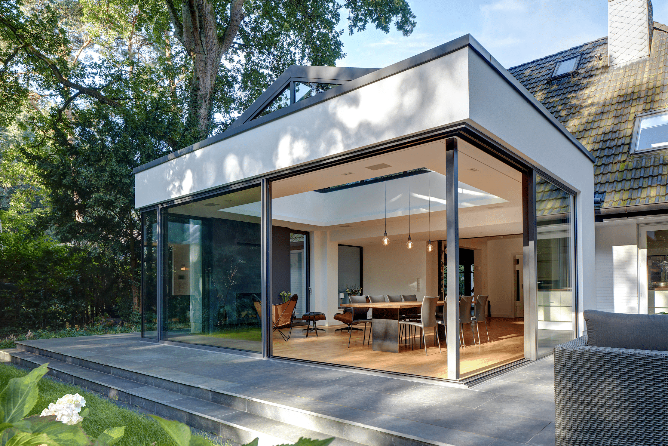 Wohnhaus mit Essbereich in einem Zubau in Wintergarten-Optik mit einer Glasfront bestehend aus deckenhohen Glas-Schiebetüren und einer Glaskuppel von Solarlux.