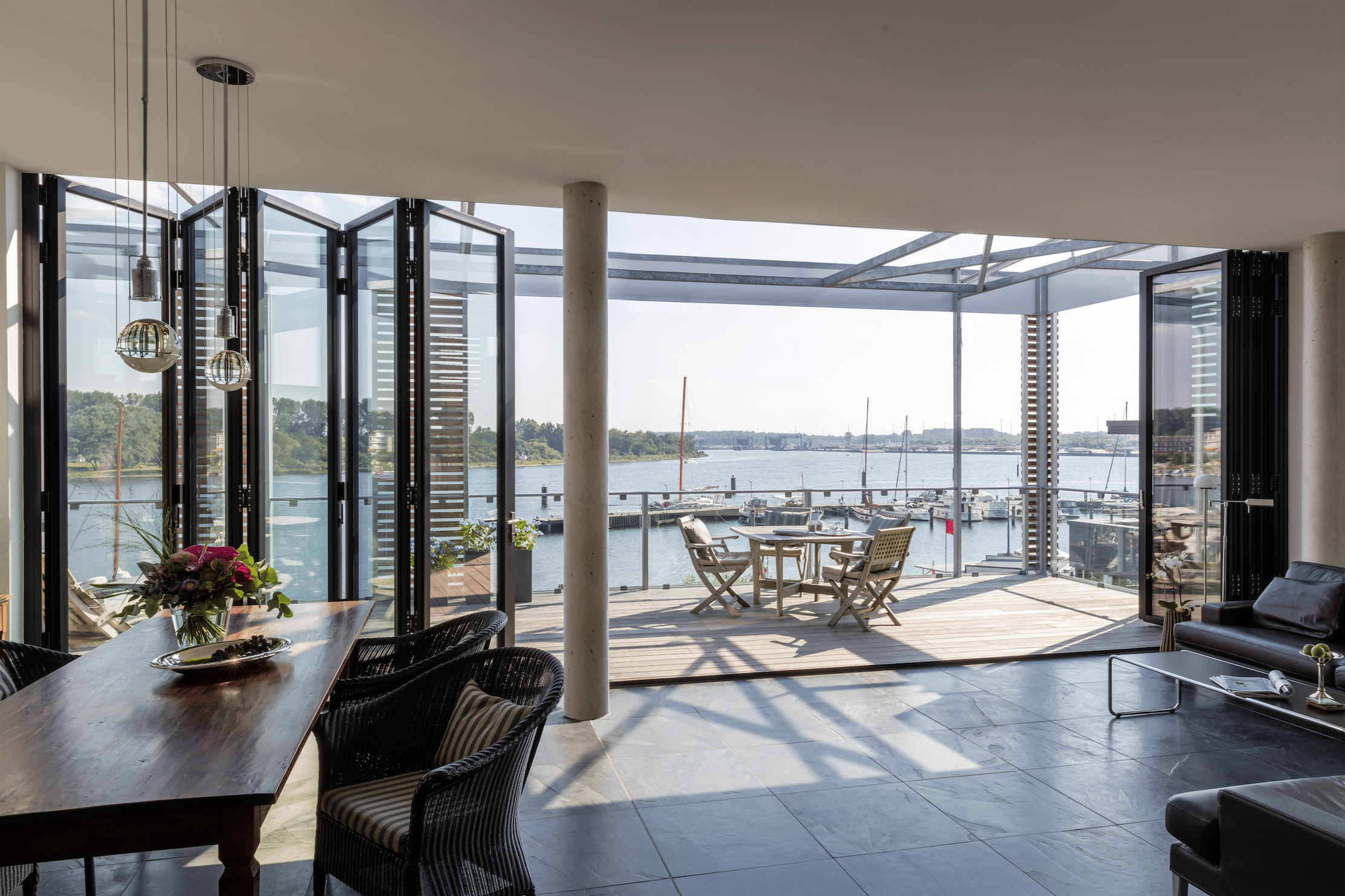 Wohnbereich mit Terrasse und deckenhohen Glas-Falt-Schiebetüren in schwarz von Solarlux.
