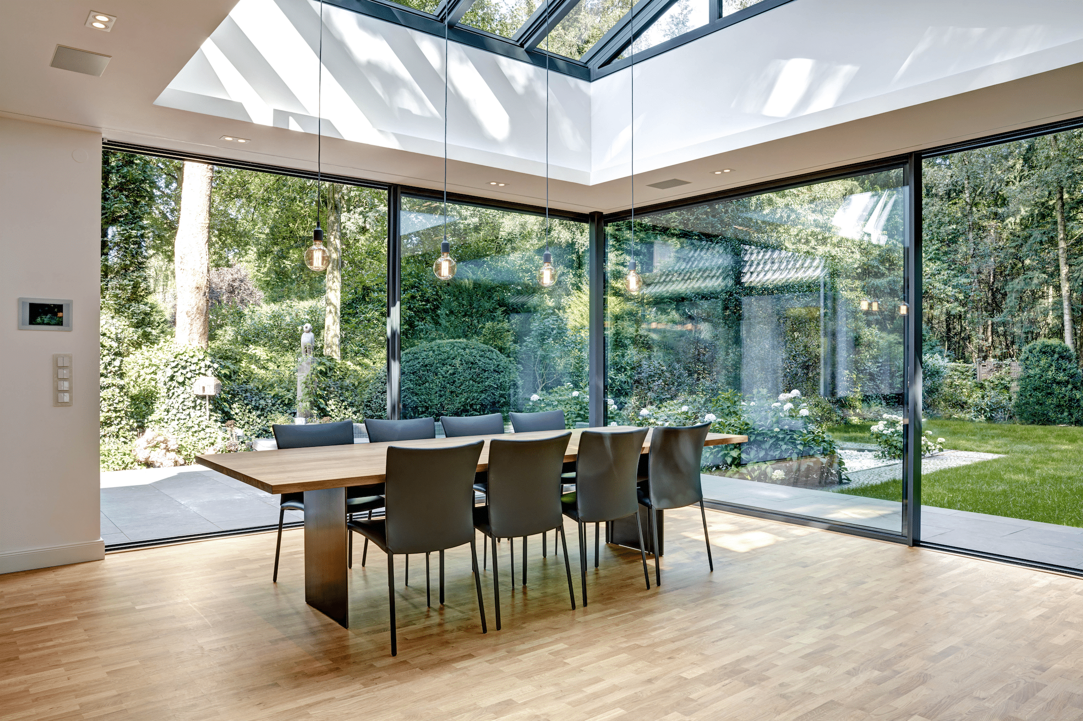 Heller Essbereich in einem Wintergarten mit Dachkuppel-Fenster und deckenhohen Glas-Falt-Schiebetüren von Solarlux.