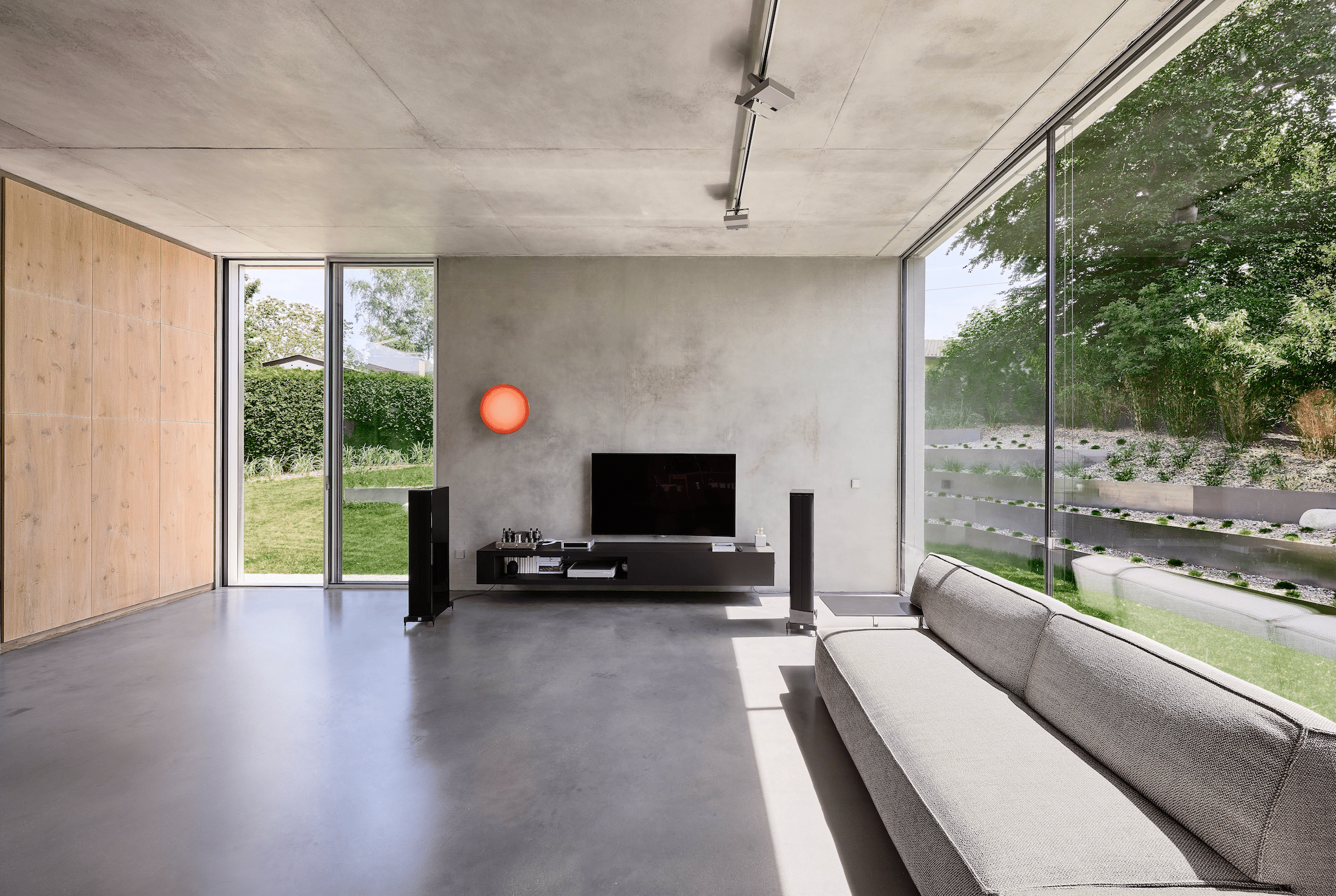 Helles Wohnzimmer in Betonoptik mit deckenhohen Glasschiebetüren von Solarlux.
