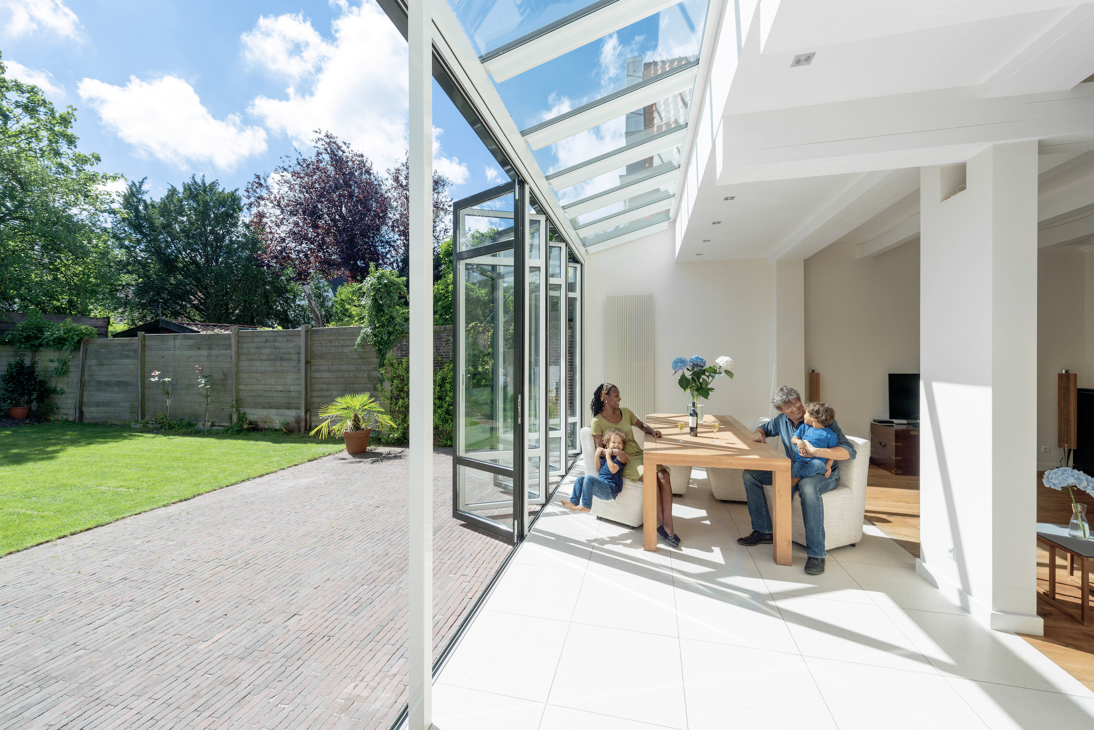 Wintergarten mit Glasfront bestehend aus Dachfenstern und deckenhohen Glas-Falt-Schiebetüren in weiß von Solarlux.