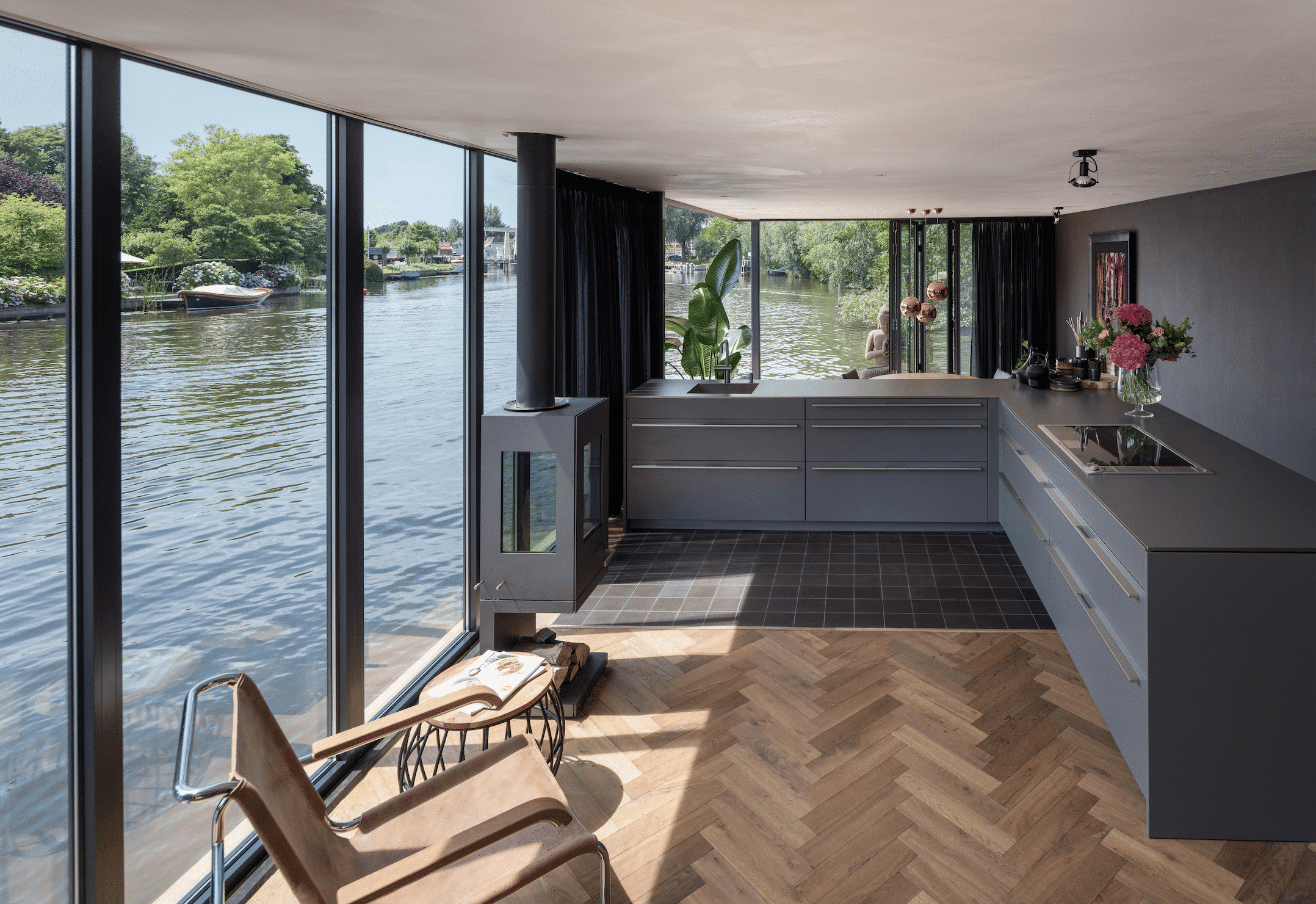 Hausboot mit Fischgret-Holzboden und deckenhohen Glas-Schiebetüren von Solarlux.