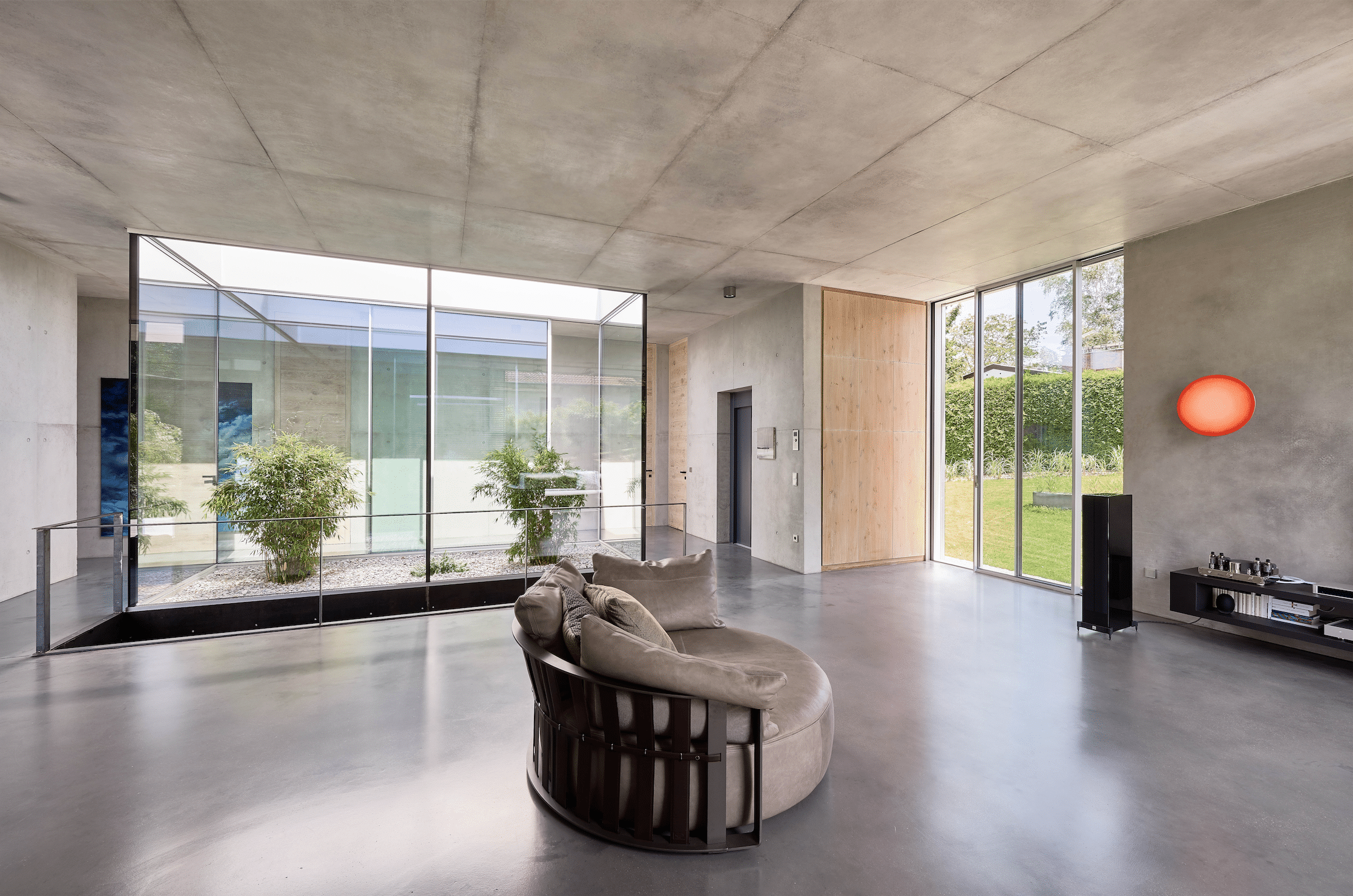 Helles Wohnzimmer in Betonoptik mit deckenhohen Glasfenstern und -türen von Solarlux.