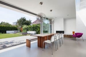 Heller Wohnbereich mit Kamin, Terrasse und deckenhohen Glas-Schiebetüren von Solarlux.