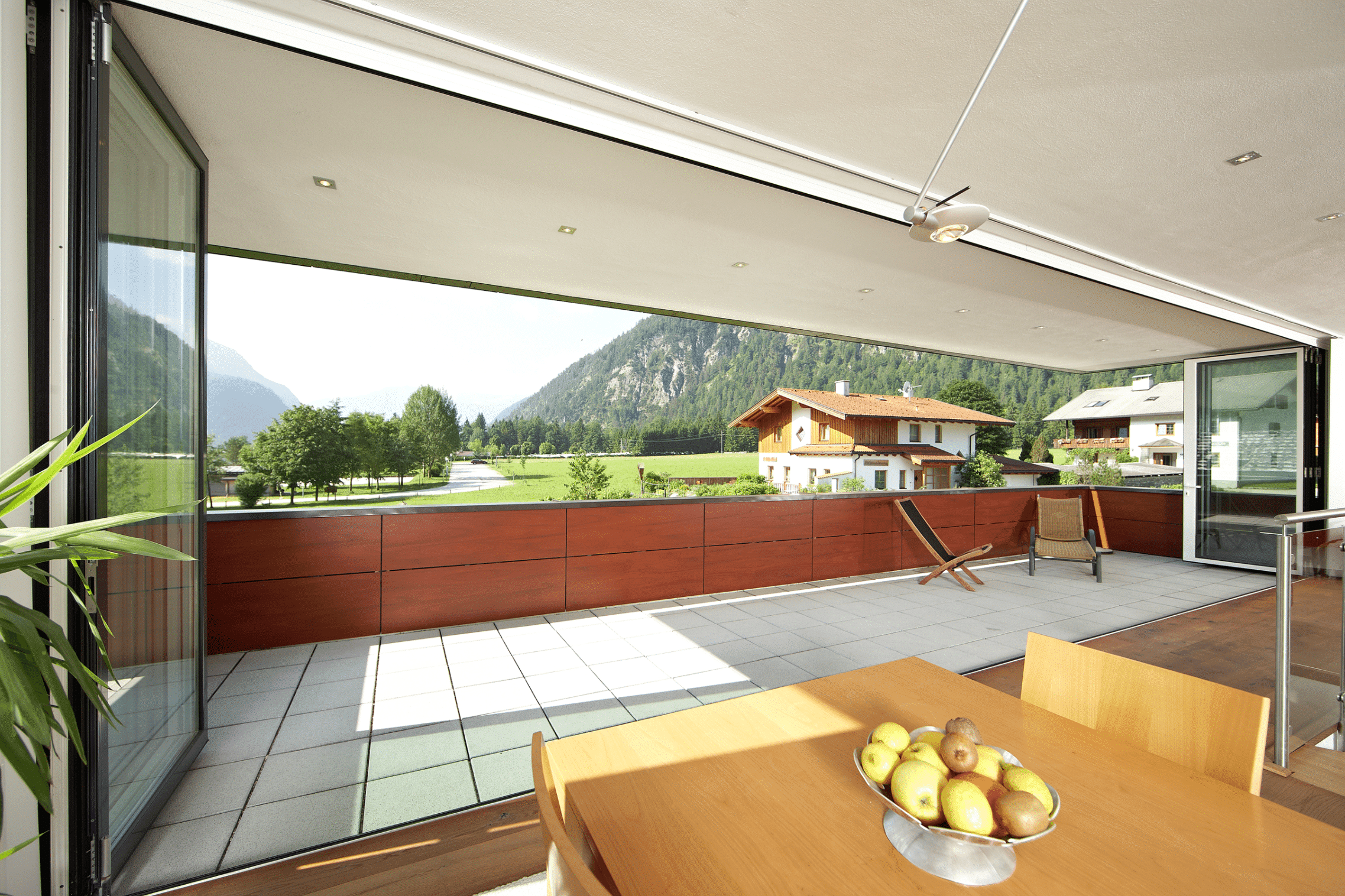 Offenes Esszimmer mit kompletter Glasfront zum Balkon hin, bestehend aus Glasfalttüren von Solarlux.