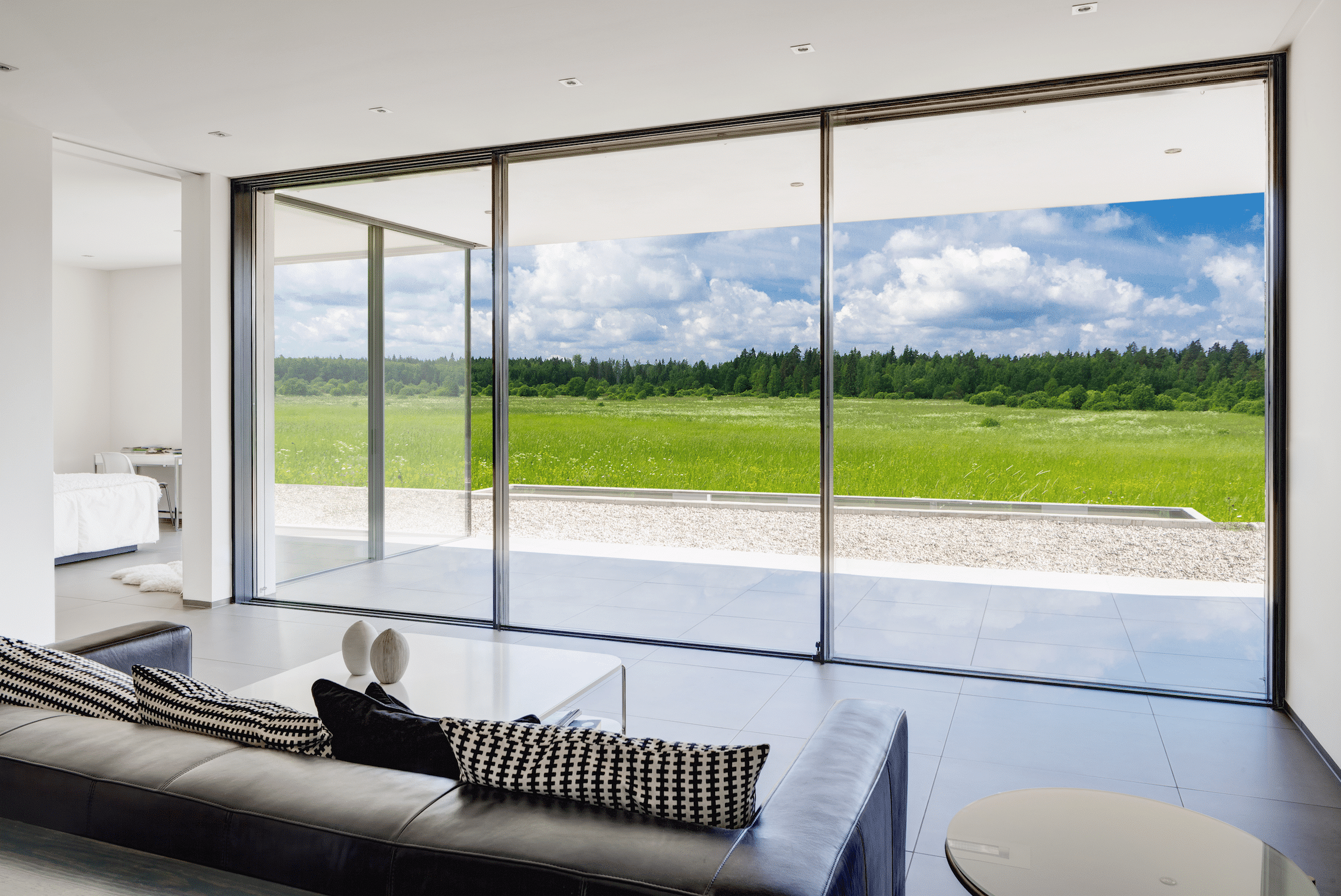 Heller, offener Wohnraum mit Panoramablick dank deckenhoher Glasfront zur Terrasse hin, bestehend aus Glasschiebetüren von Solarlux.
