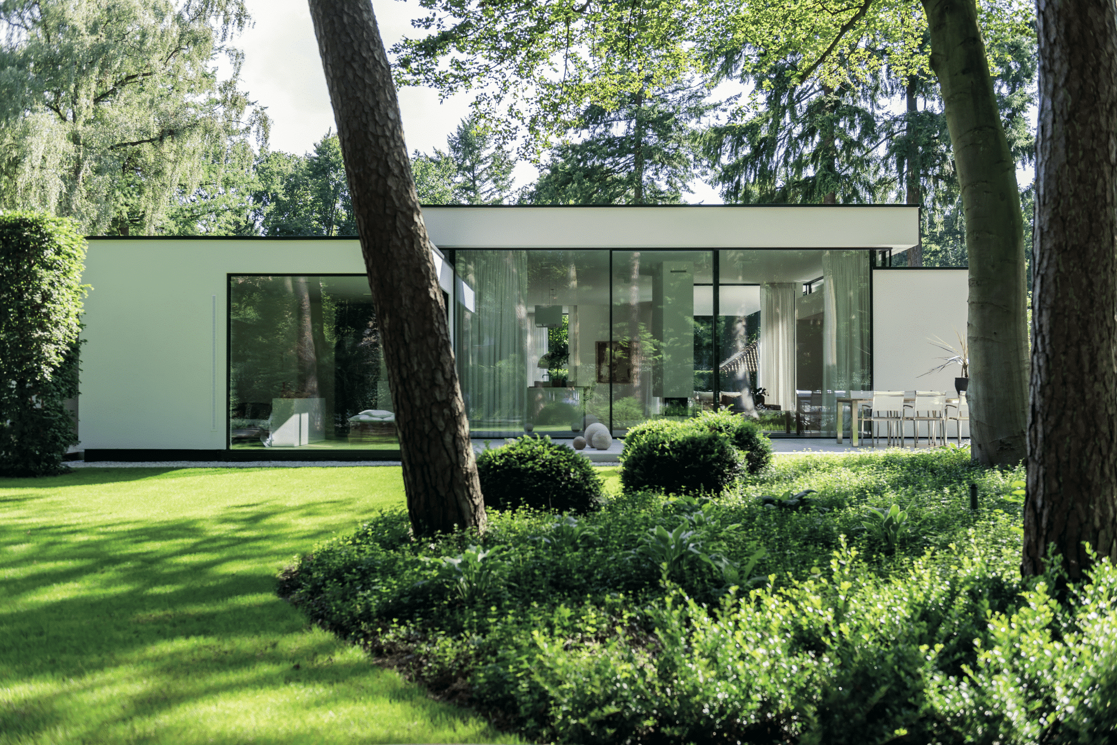 Solarlux zeigt ein weißes,modernes Haus mit ansprechendem Garten, durch die Glasfaltwand kommt man direkt in den Wohn-Essbereich.