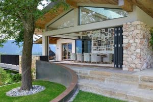 Solarlux zeigt ein Terrassenhaus aus Stein mit Essecke darin, vielen Fotos und einer Glasfaltwand die direkt raus zu einer Treppe führt.