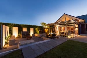 Solarlux zeigt eine Terrasse mit gemütlicher Lounge und Sitzbänken, durch eine Glasfaltwand kommt man genau in den Wintergarten.