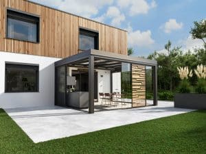 Solarlux zeigt eine Terrasse mit barrierefreiem Wintergarten aus Glasschiebeelemten, welcher zum einem Einfamilienhaus mit Holzfassade dazu gehört.