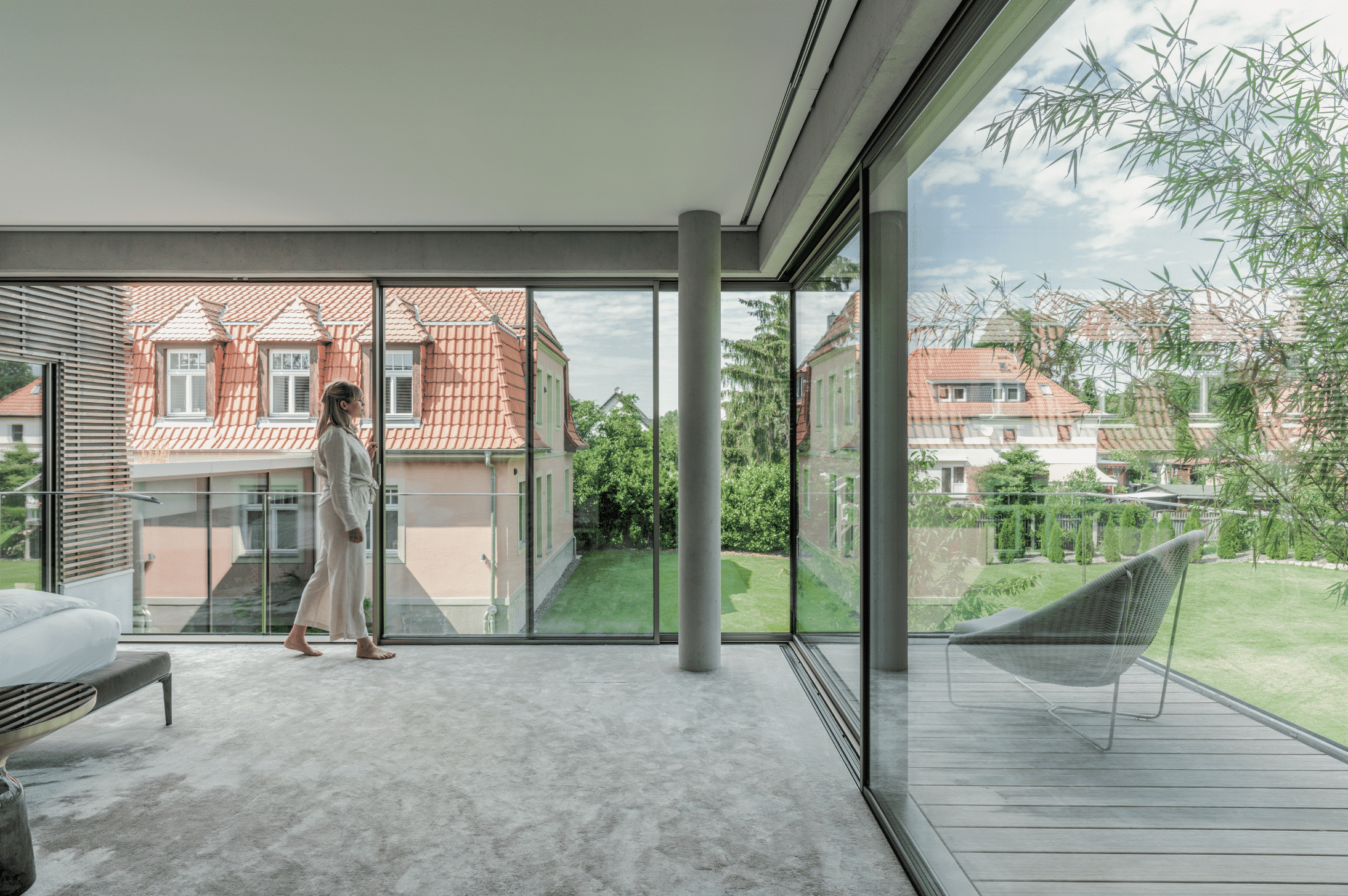 Solarlux zeigt Schlafzimmer mit vollverglasten Fronten mit bodentiefen Fenstern und Glasschiebetür auf de Balkon.
