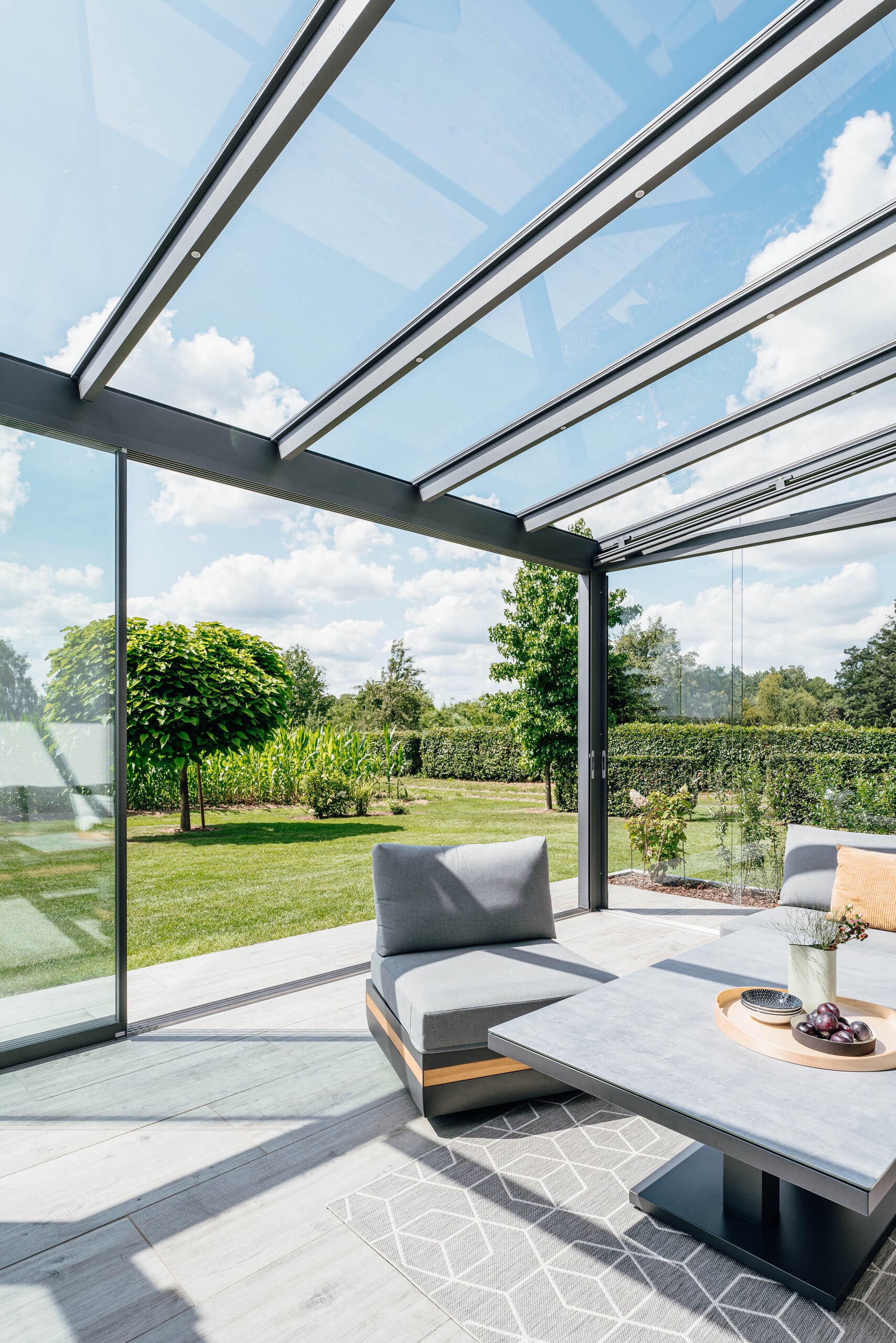 Solarlux zeigt lichtdurchfluteten Wintergarten aus Alu und Glas mit Glasschiebetüre mit Blick in den Garten.