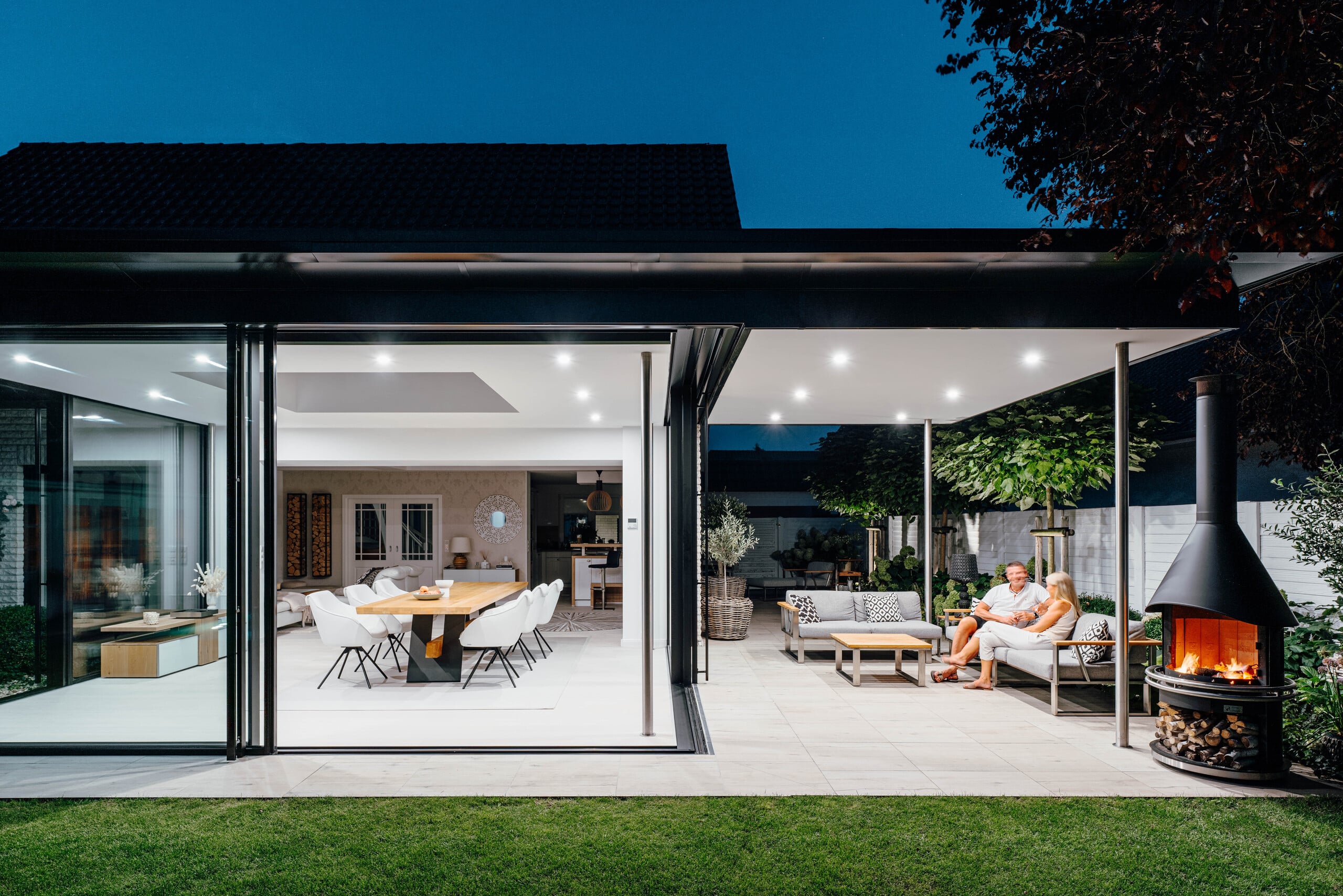 Solarlux zeigt Wintergarten mit Glasschiebetüren mit schwarzen Rahmen, die barrierefrei auf die Terrasse führen.