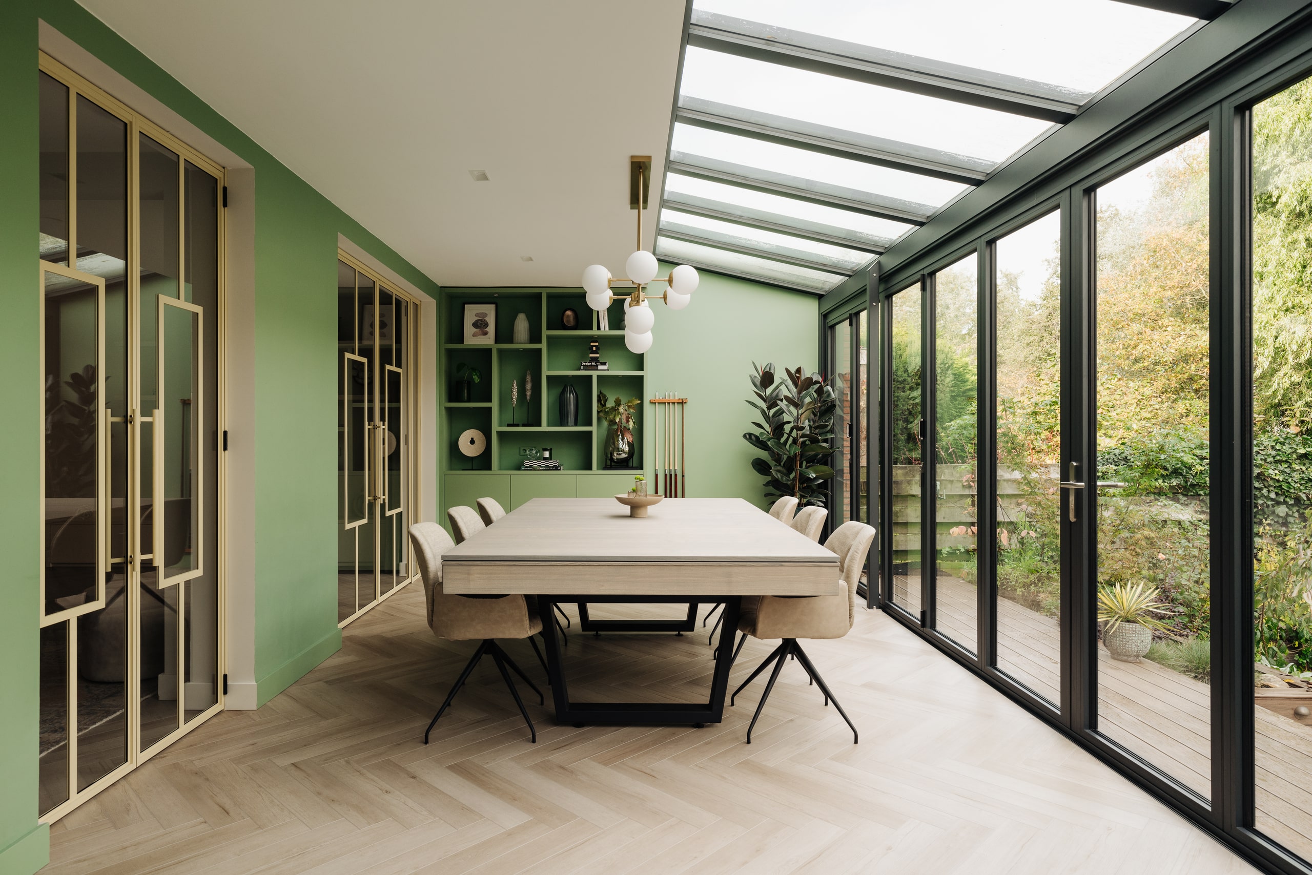 Grosser Wintergarten mit Esstisch, Glasdach und Glasfaltwänden von Solarlux der barrierefrei in den Garten führt.