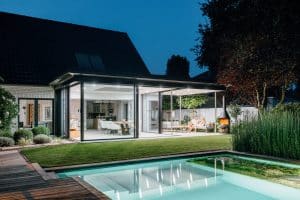 Solarlux zeigt Wintergarten mit Glasschiebetüren mit schwarzen Rahmen, die barrierefrei auf die Terrasse führen.
