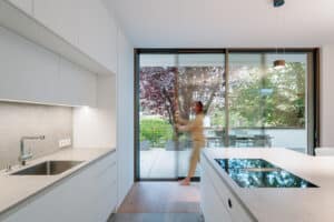 Ein modernes Einfamilienhaus mit großflächigen Schiebetüren „Cero III“, die Küche und Wohnbereich mit dem Außenbereich verbinden.