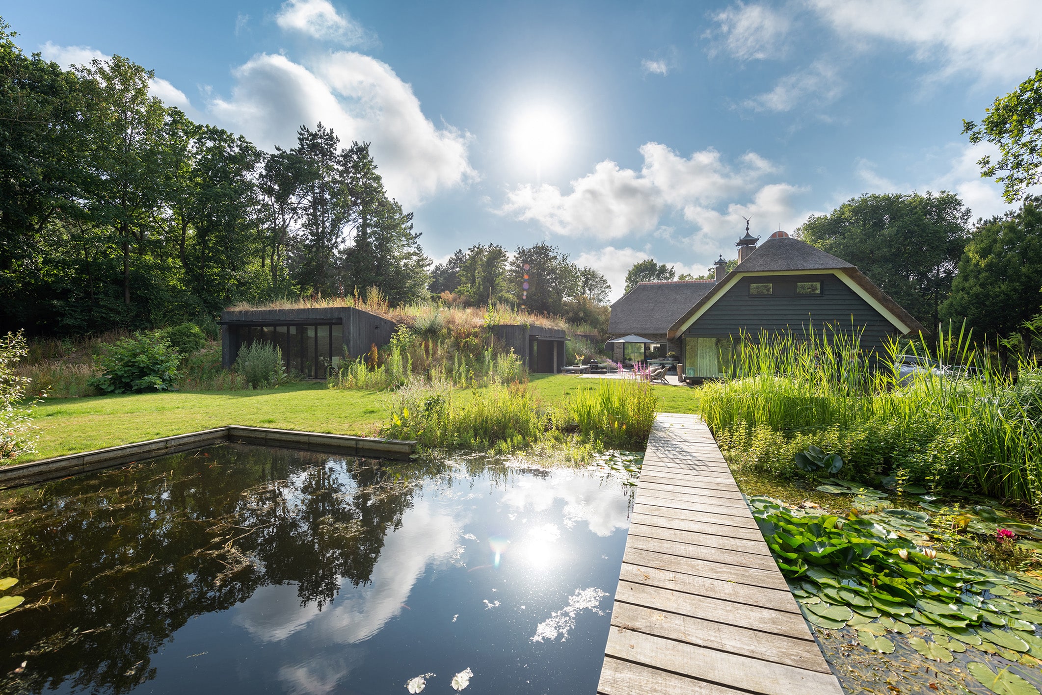 Teich mit Wohnhaus und verstecktem Hallenbad im Hintergrund.