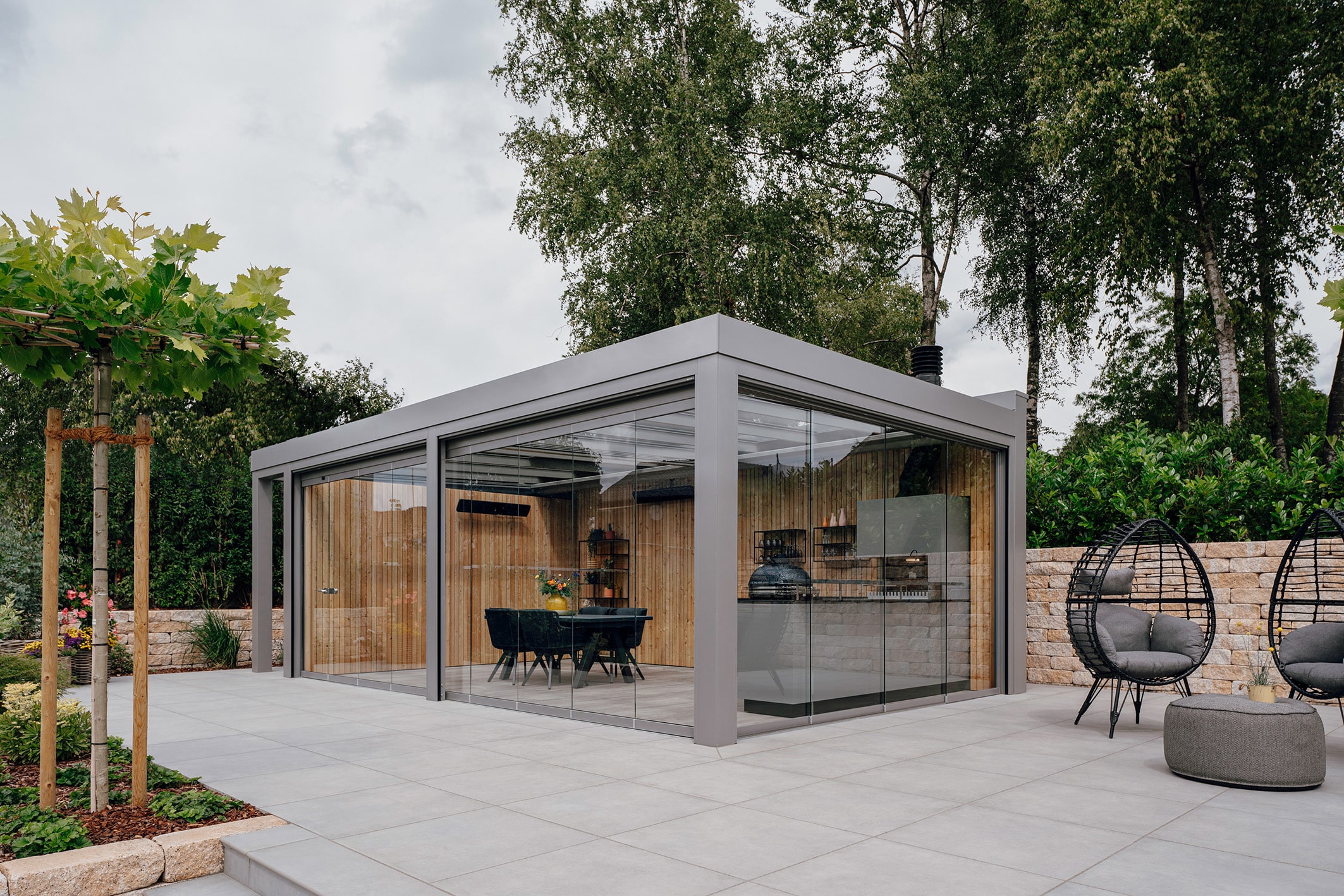 Glashaus Acubis von Solarlux mit vollausgestatteter Outdoorküche und geschlossenen Seitenelementen aus Glas.