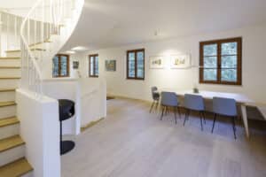 Solarlux präsentiert ein fertig saniertes Einfamilienhaus mit großem offenen Wohnbereich mit Esstisch und freiem Treppenaufgang.