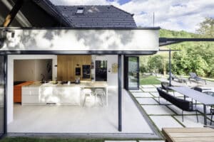Solarlux präsentiert ein saniertes Einfamilienhaus mit großer offener Küche, Essbereich und Glasfaltwänden an zwei Seiten, die zur Terrasse hin geöffnet werden können.