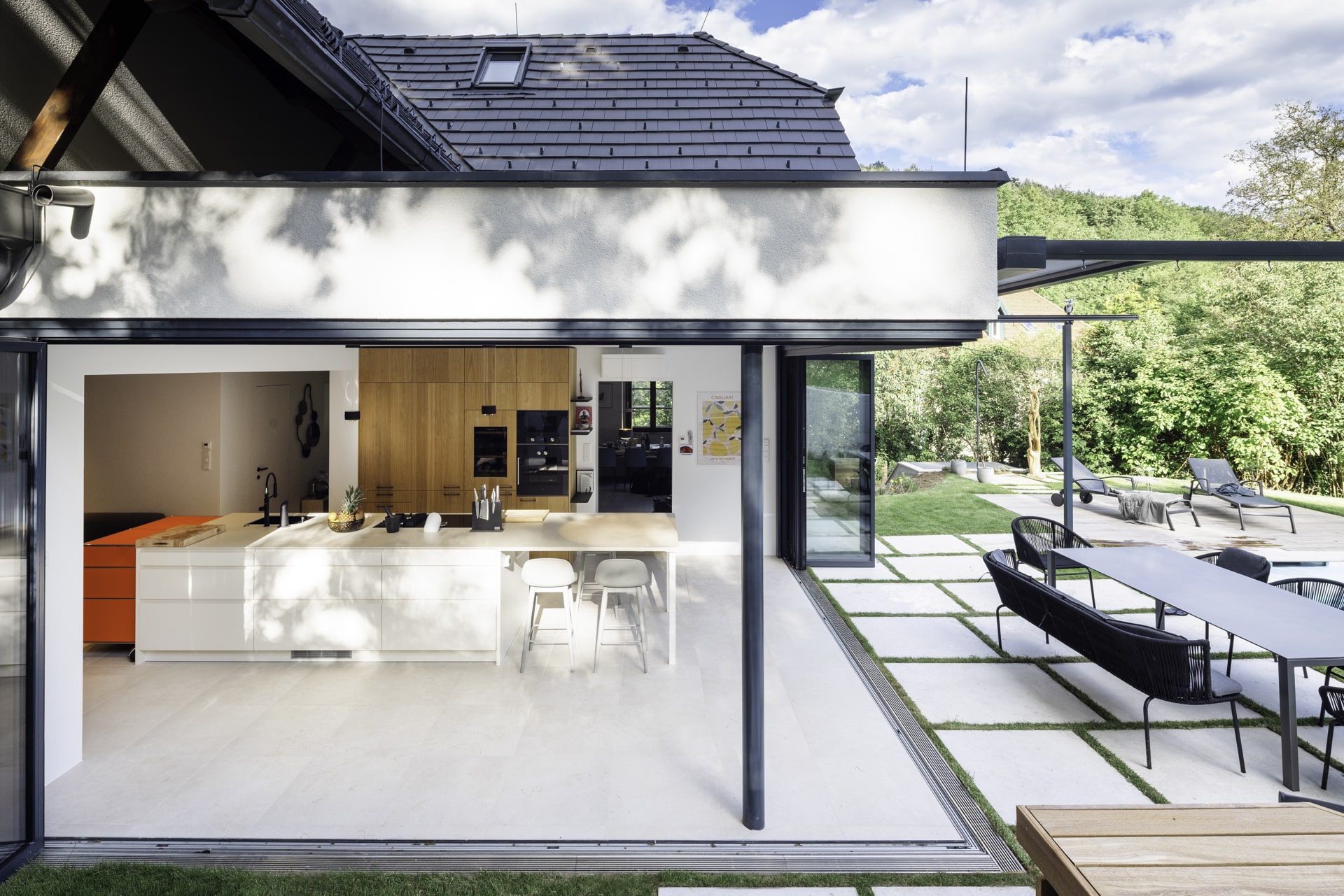 Solarlux präsentiert ein fertig saniertes Einfamilienhaus mit großer offenen Küche mit Essbereich und Glasfaltwänden an zwei Seiten, die zur Terrasse hin geöffnet werden können.