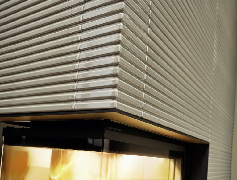 Kamin mit Verkleidung aus glänzend beigen Keramikmosaikfliesen in einem Stab und Rillendesign von Sommerhuber.