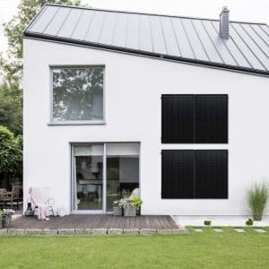 Weißes Einfamilienhaus mit Holzterrasse und Photovoltaik-Module von SONNENKRAFT an der Wand montiert.