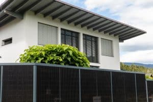 Einfamilienhaus mit Garten und einem hohen, modernen Solarzaun mit anthrazitfarbenem Rahmen von Sonnenkraft.