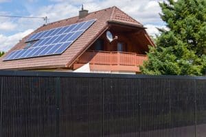 Einfamilienhaus mit dachmontierten Solar-Modulen und einem hohen Solarzaun mit schwarzem Rahmen von Sonnenkraft.
