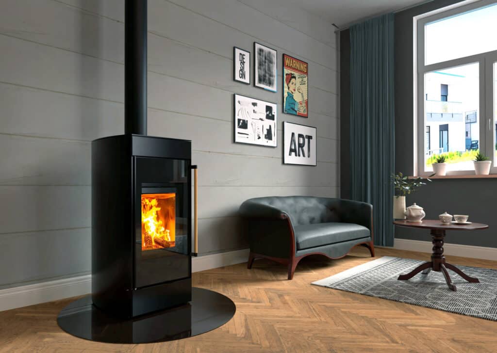 H Stocker präsentiert den wassergeführten Kaminofen Seespitz in Schwarz mit schwarzer ovaler Funkenschutzplatte in einem Wohnraum.