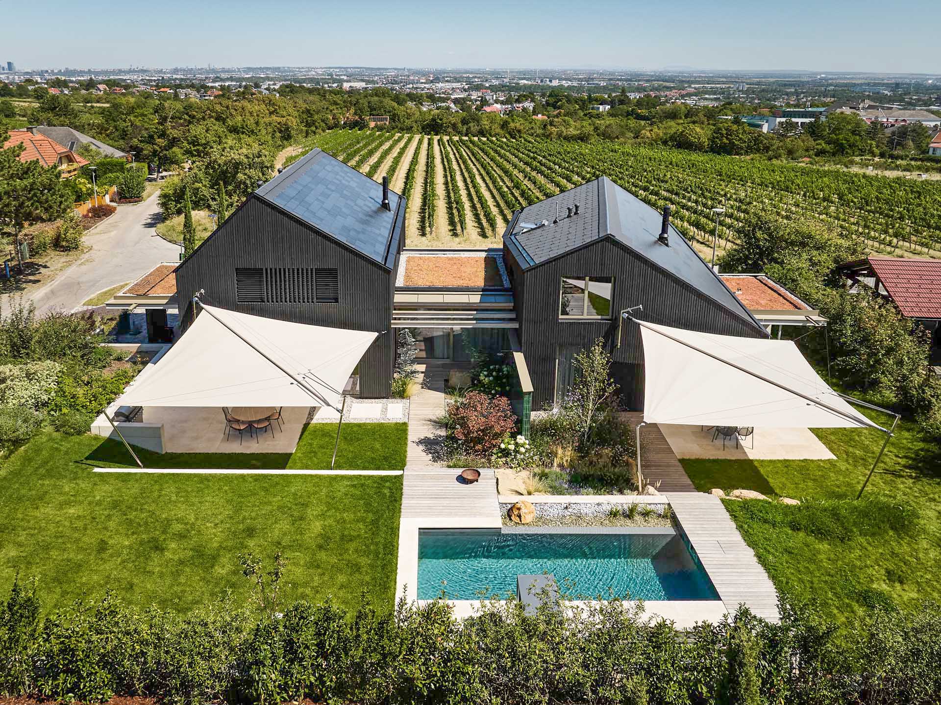 SunSquare Shading Solutions präsentiert ein Doppelhaus mit Pool, dessen Terrassen durch zwei zusammenrollbare Sonnensegel beschattet werden.