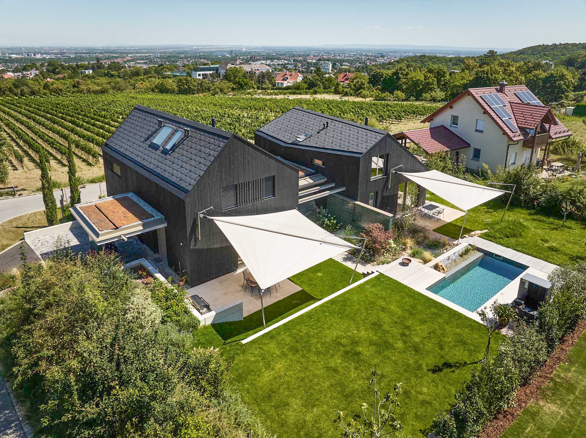 SunSquare Shading Solutions präsentiert ein Doppelhaus mit Pool, dessen Terrassen durch zwei zusammenrollbare Sonnensegel beschattet werden.