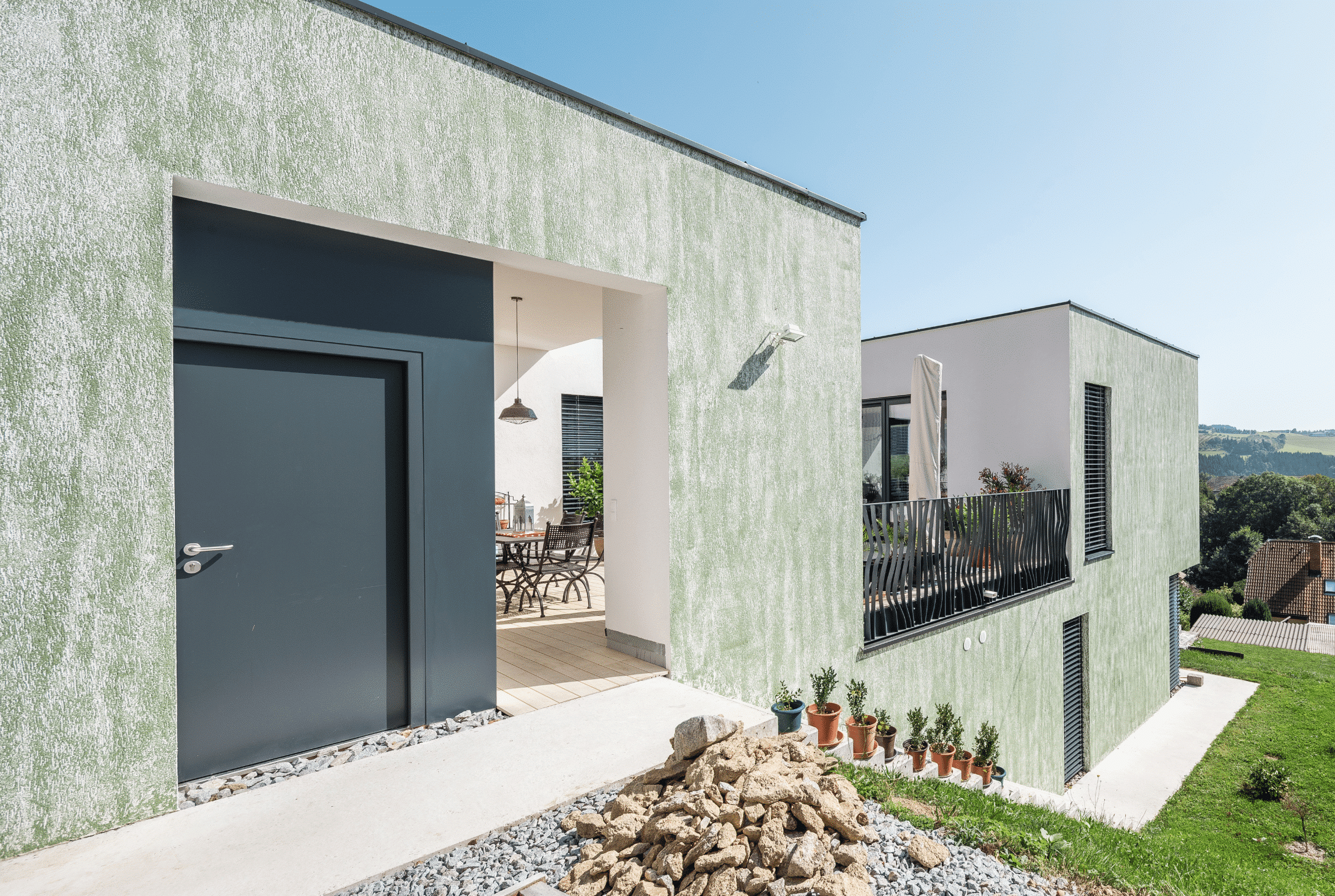 SynthesaGruppe zeigt modernes Flachdach-Wohnhaus der Hanflinie mit Rauputz und Außenstiege und Terrasse.