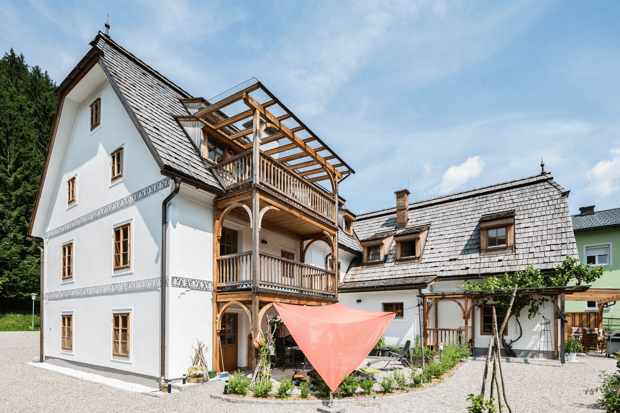 SynthesaGruppe zeigt ein weisses Haus im ländlichen Stil mit mehrstöckigem Balkon aus Holz und gläserner Überdachung und Fenstern mit Holzrahmen.