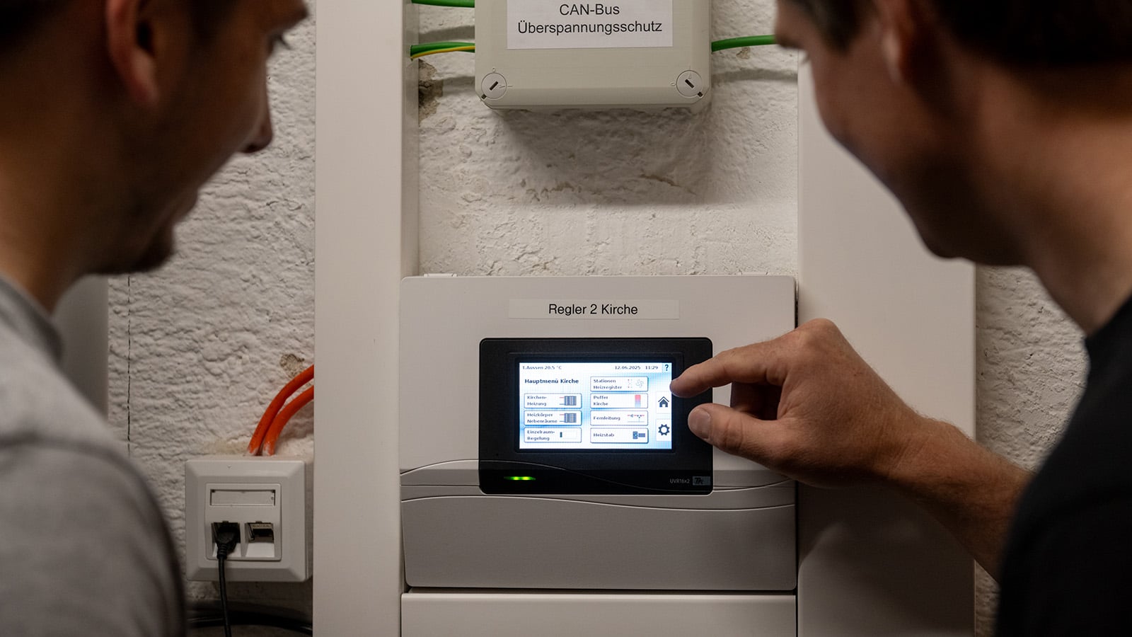 Technische Alternative RT zeigt den Heizungsregler mit Touchscreen in einer Kirche.
