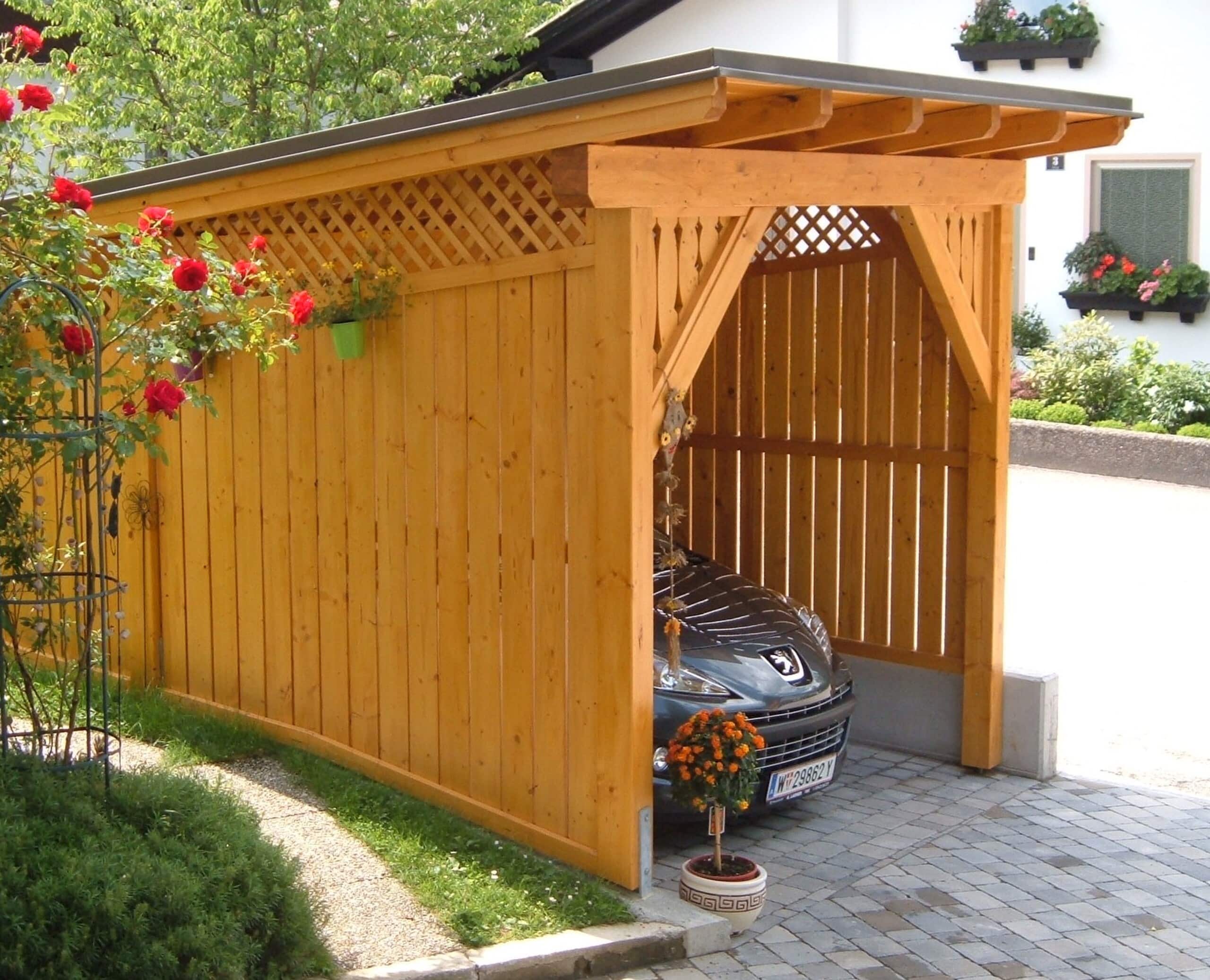 Rustikales Carport aus Holz mit Holzgitter, Zierelementen und einem Schrägdach aus Blech von Richad Teufel.